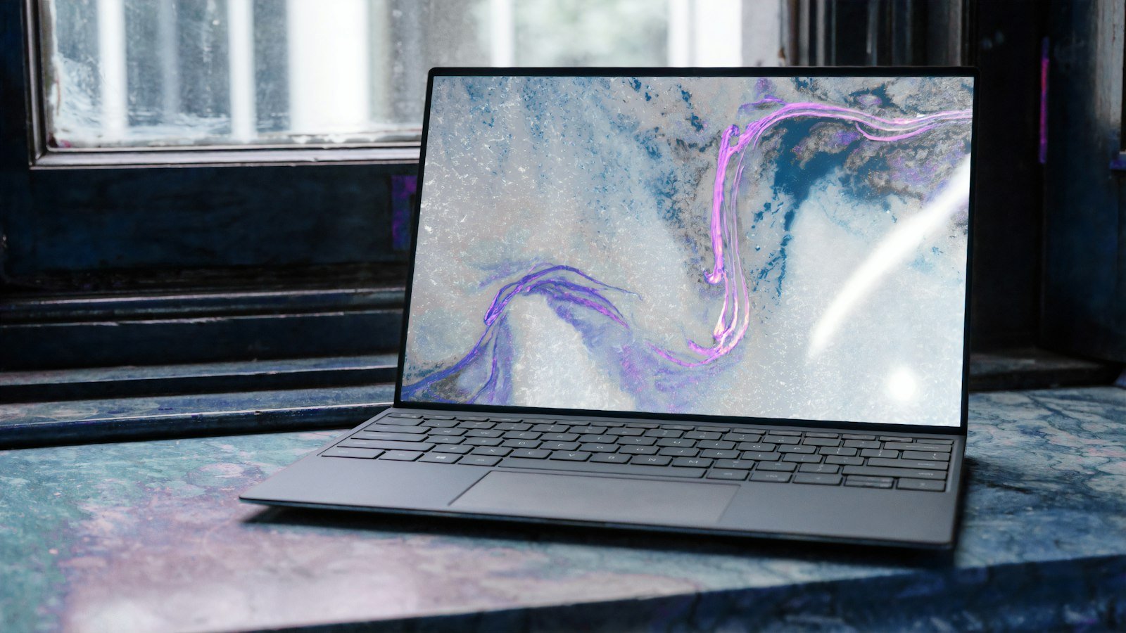 Laptop na kamiennym parapecie, na ekranie jasna abstrakcja